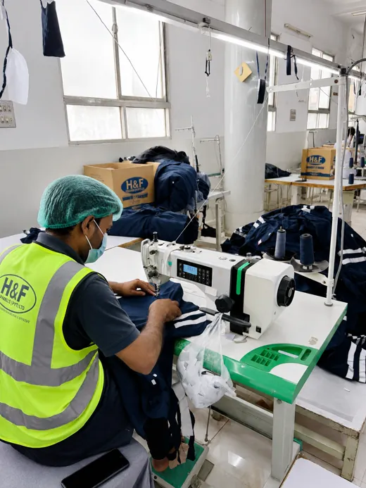 Machinist in an H&F high-visibility vest sewing a garment