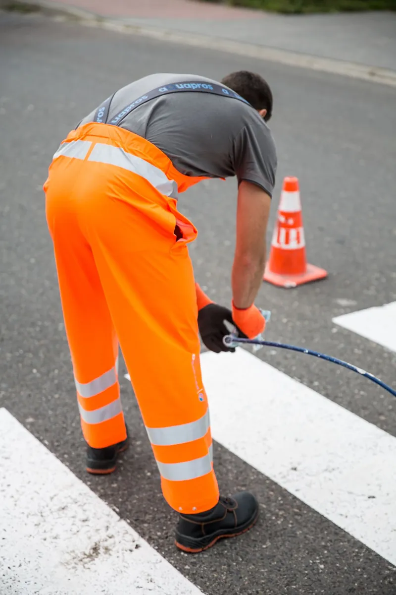 Road worker in fluorescent orange high-visibility trousers with reflective bands
